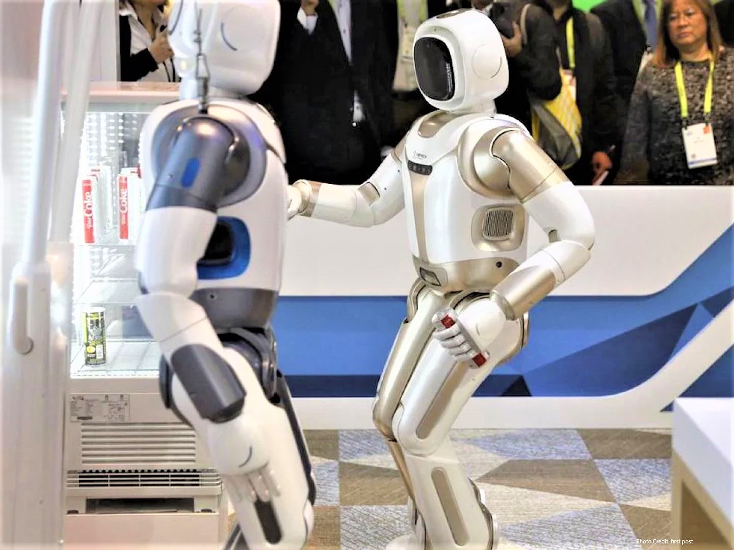  A pair of white and gold colored Nao humanoid robots stand on display at a technology convention.